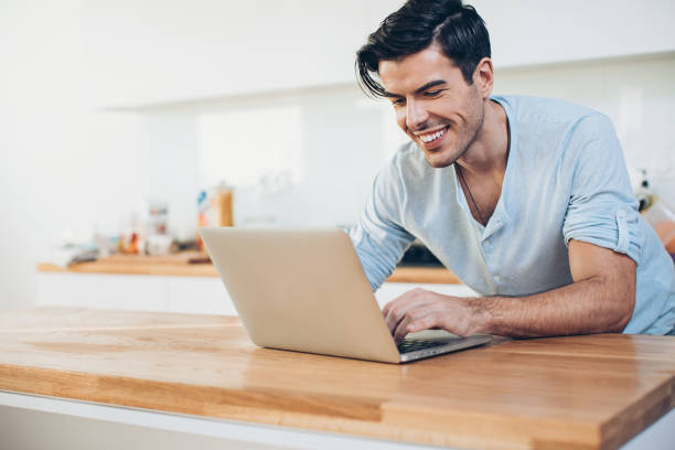 istock Young man with laptop in the kitchen 1217230510