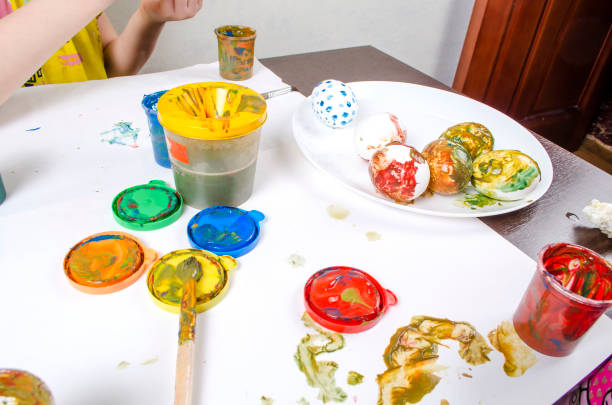 A table with paints and brushes prepared for coloring eggs. Easter preparation