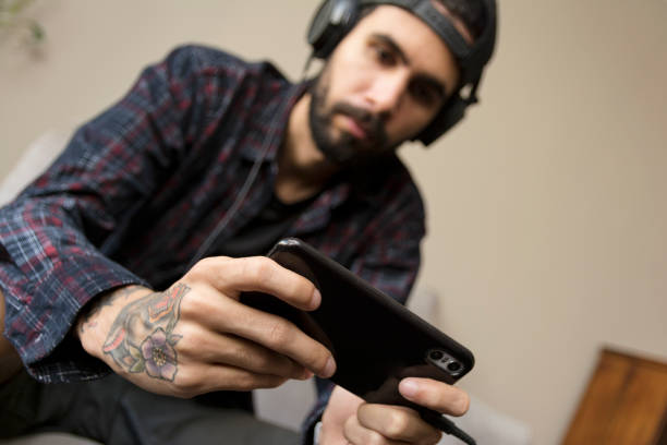 istock Young man paying a mobile game at home. Smart phone gaming 1217234616