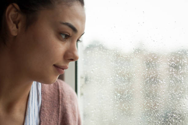 istock young woman looking out window 1217237860