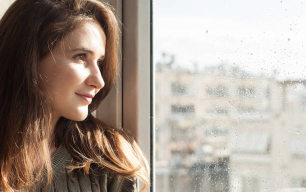 istock young woman looking out window 1217237891