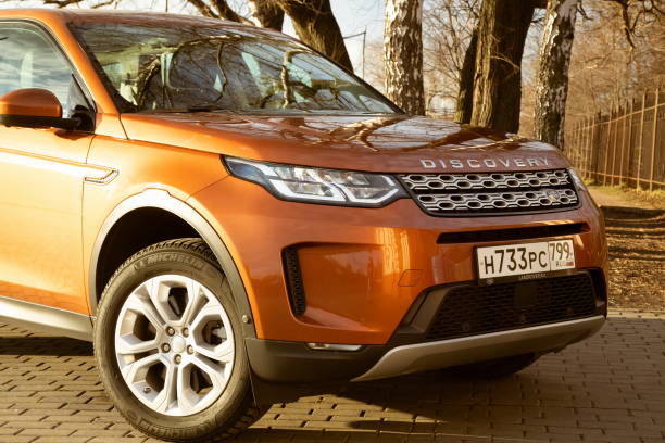 wszystkie nowe land rover discovery sport 2019 jest zaparkowany na terenie parku. z bliska widok z boku. reflektory, zderzak i kaptur pomarańczowego suva, srebrne koła, - hood car headlight bumper zdjęcia i obrazy z banku zdjęć