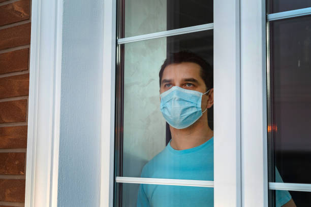 Man with a protective medical mask at the window