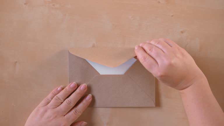 SLO MO LD Hands opening a brown envelope and taking out a sheet of paper