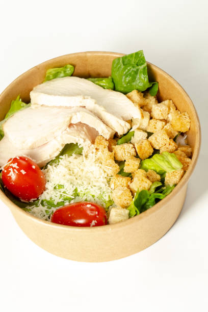 istock White isolated background, in a cardboard plate or package, Caesar salad with chicken, lettuce, cherry tomatoes 1217245117