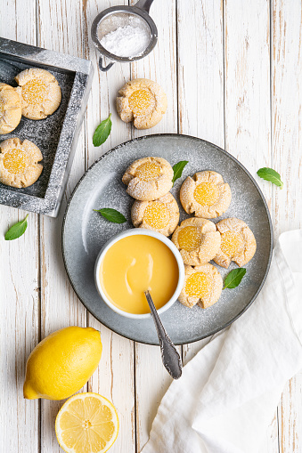 Delicious sweet snack, lemon crud thumbprint cookies sprinkled with powdered sugar on rustic wooden background