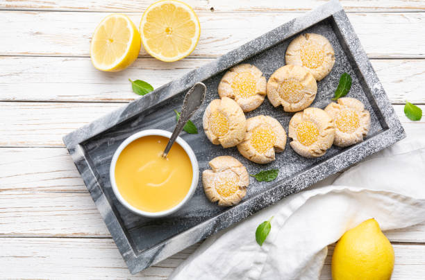 Delicious sweet snack, lemon crud thumbprint cookies sprinkled with powdered sugar Delicious sweet snack, lemon crud thumbprint cookies sprinkled with powdered sugar on rustic wooden background crud stock pictures, royalty-free photos & images