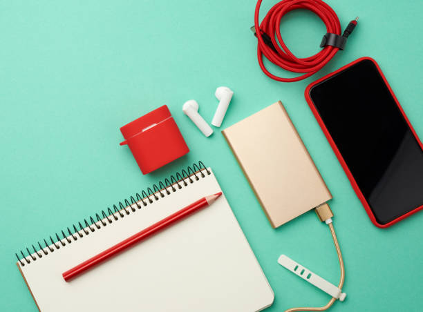 istock paper notebook, power bank with cable, red smartphone with blank black empty screen, headphones 1217245834