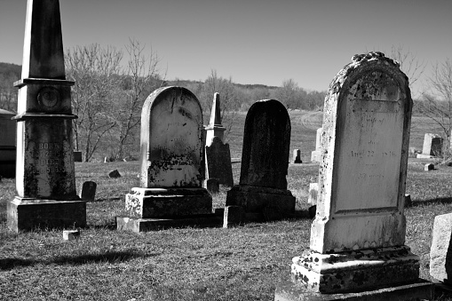 Old cemetery in rural farmland with grave sites dating back to the 18th century. Black and White.