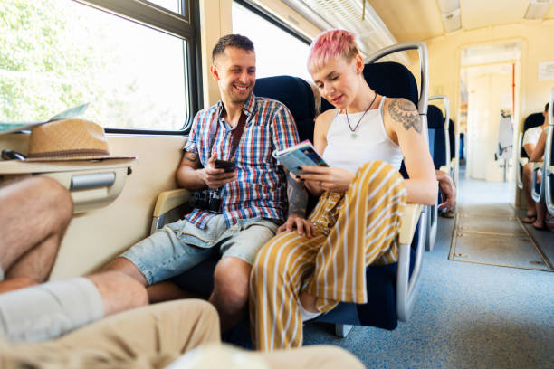 istock Young caucasian couple using tourist book and phone for directions while riding on train 1217246835