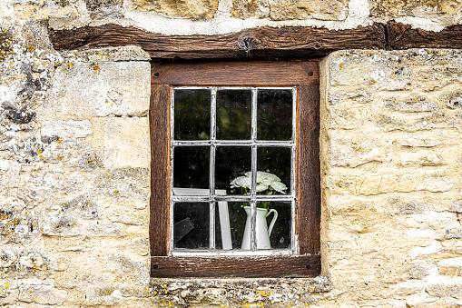 A closeup shot of a flower vase on an outside windowsill behind metal window bars