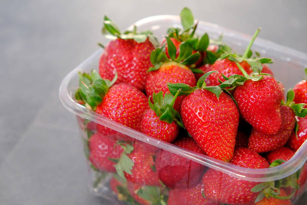 istock 1 kg fresh strawberries in plastic box, on gray wooden background 1217250095