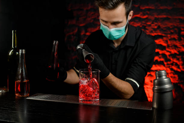 istock Bartender accurate pours alcoholic drink into large glass with ice. 1217251127