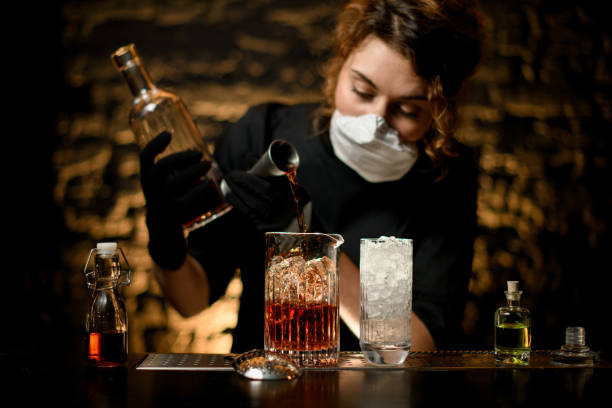 istock Lady bartender pours alcoholic drink into large glass with ice. 1217251982
