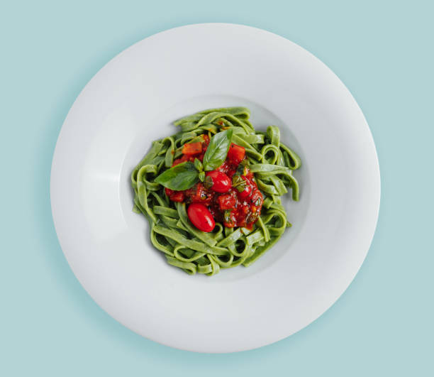 istock Spaghetti pasta with homemade spinach sauce, green spaghetti, fried tomatoes and fresh basil leaves, vegetarian foodclose-up on a white background . top. view from above 1217252222