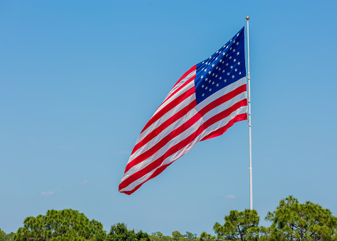 Clear blue sky and American flag waving in the wind.