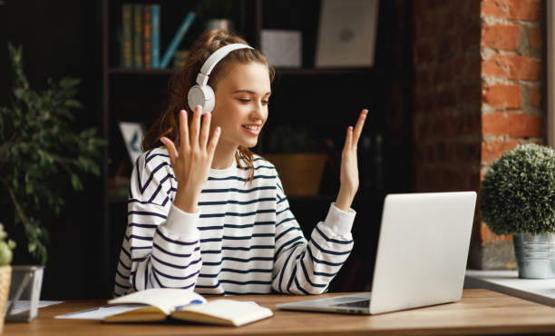 istock Excited woman in headphones having conversation on video chat while using laptop at home 1217255343