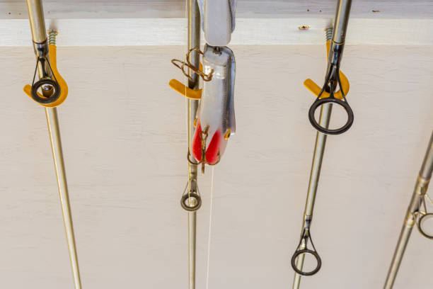 Rods stored on a ceiling inside of a garage. Fishing rods and one lure hanging from a white ceiling.