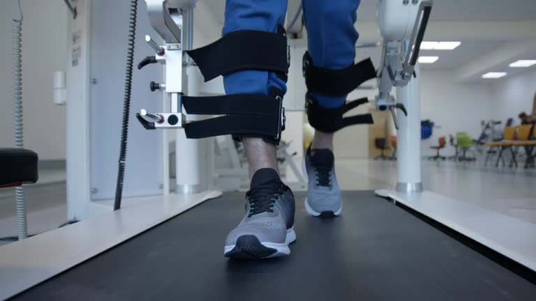 Front view close up of man walking with the help of a exoskeleton robot on treadmill