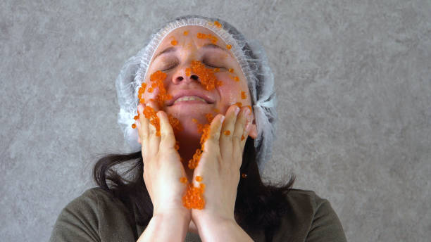 女性は彼女の顔に赤いキャビアを塗りつぶす - caviar salmon red gourmet ストックフォトと画像