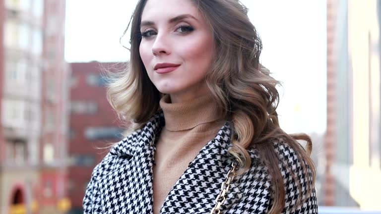 Attractive girl in a coat in the street in a city, sun is shining