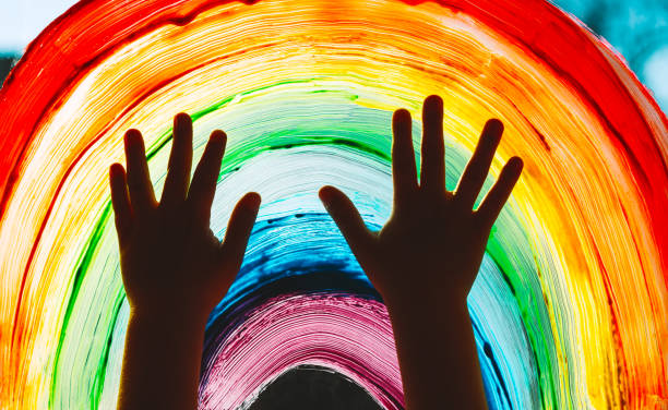close-up photo of child's hands touch painting rainbow on window. family life background. image of kids leisure at home, childcare, safety joy symbol. - educação ilustrações imagens e fotografias de stock