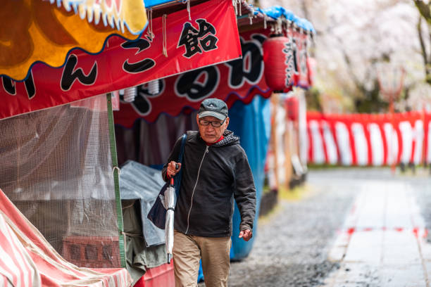 平野神社、地元の桜花見祭りで雨で雨の中を歩く男と一緒に - single lane road footpath flower formal garden ストックフォトと画像