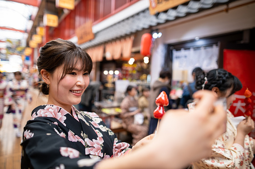 Young woman in kimono taking selfie picture with strawberry in shopping mall
