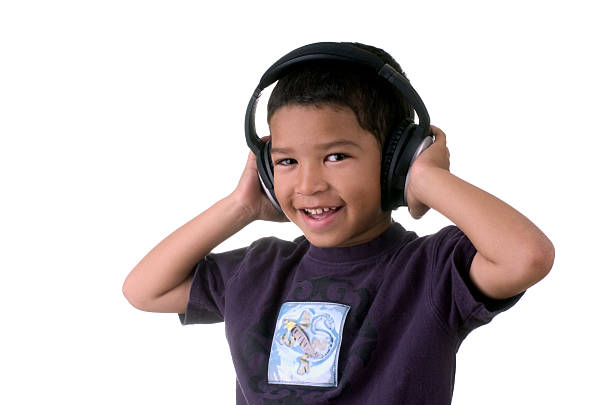 Adorable schoolboy wearing audio headset, headphones, smiling a cheerful toothy smile, looking aside at a copy space on white background. Online lesson via video link. child and technology concept