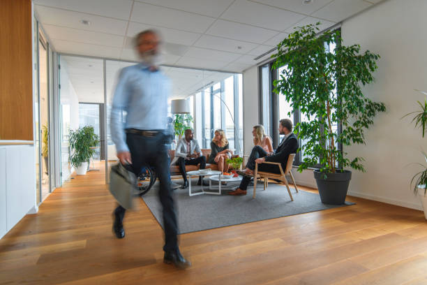 Blurred motion of mature bearded business executive moving quickly through modern office lobby on way to appointment.