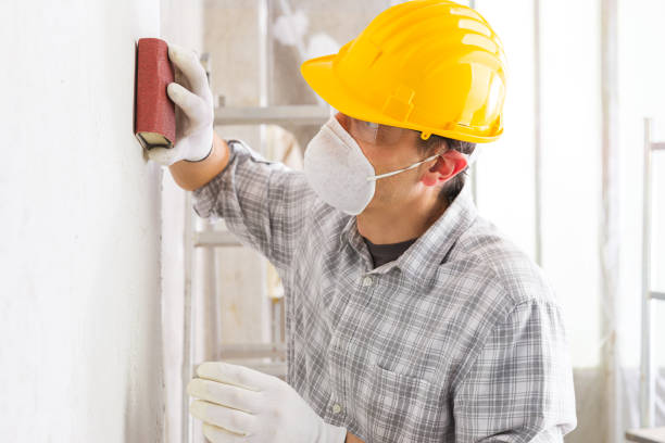 Plasterer or painter sanding a white wall stock photo