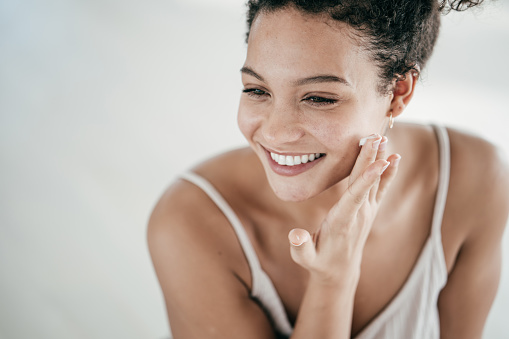 Mujeres jóvenes sonrientes que aplican crema hidratante en su rostro photo