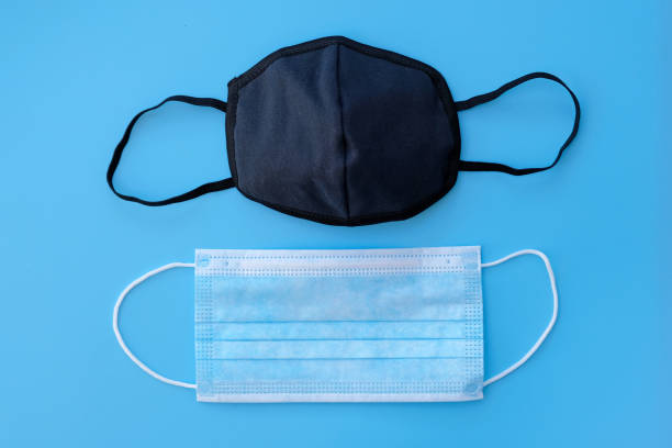 istock Disposable blue medical mask and black fabric mask with elastic bands. 1217270089