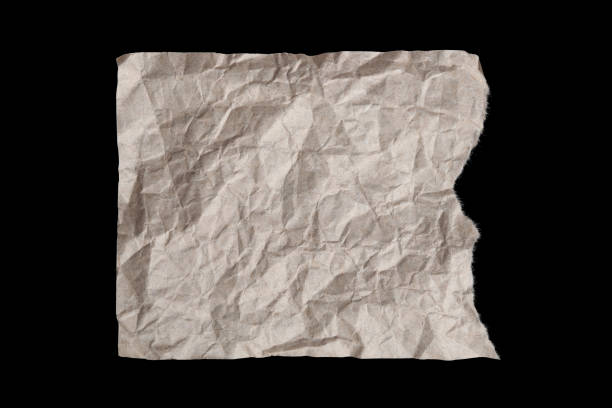 istock Torn crumpled beige paper sheet isolated on blackbackground 1217278643
