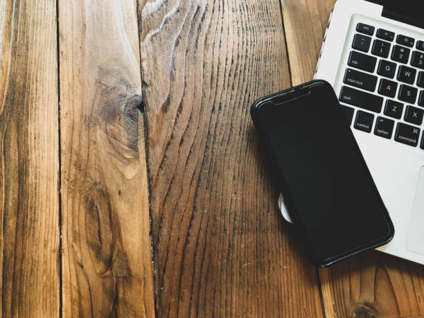 istock Phone on laptop on a wooden desk 1217281947