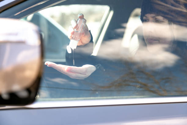 istock Woman using hand sanitizer while sitting in car 1217282722