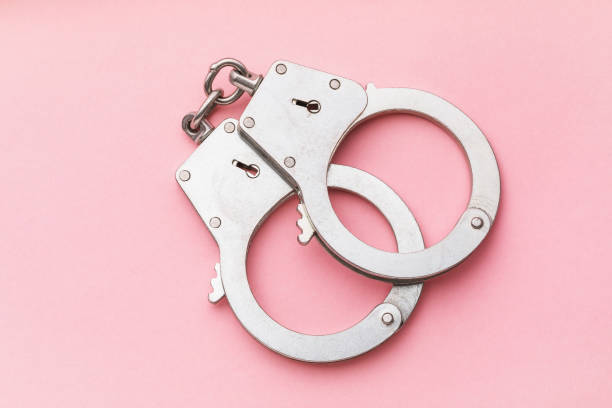 istock Closed handcuffs on a pink background, top view 1217286451
