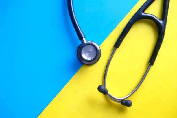 Photo of top view of stethoscope on color background