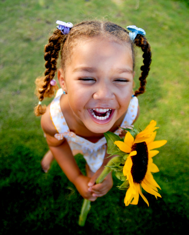 Portrait of attractive caucasian little child girl with blond curly hair and cute smile. Happy smiling child looking at camera - close-up, outdoors.
