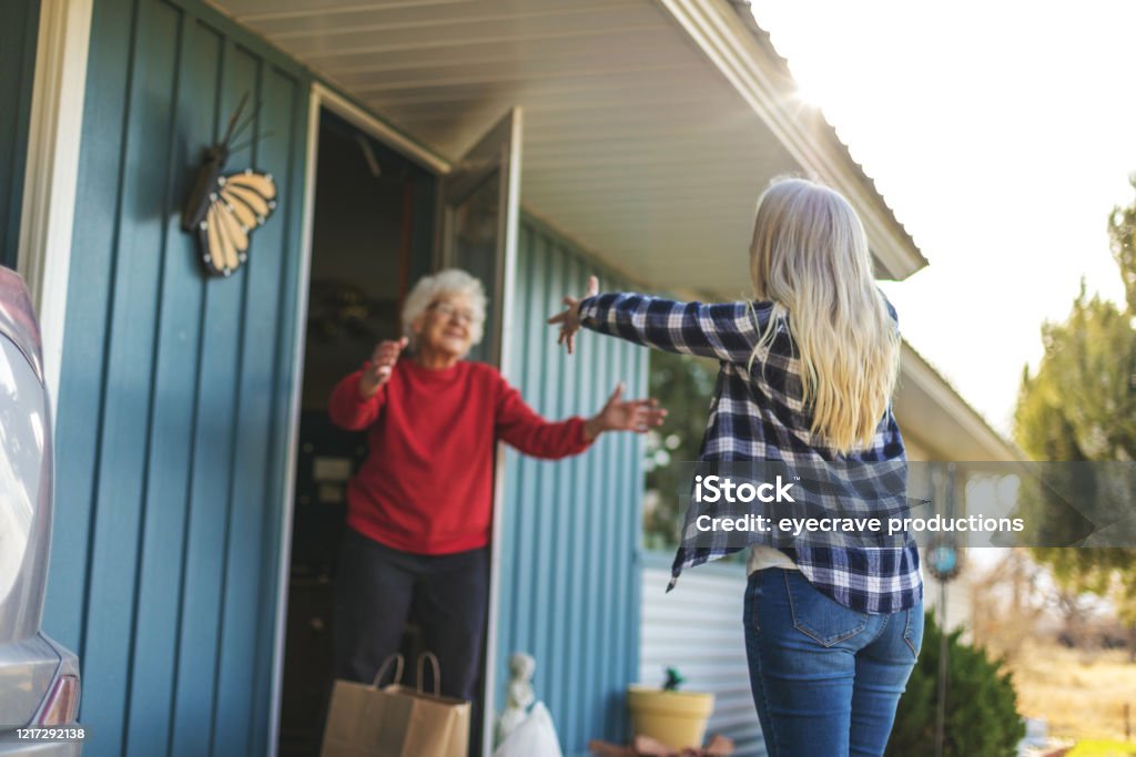 Volwassen volwassen vrouw leveren boodschappen aan senior volwassen vrouwelijke en sociale distantiëring als gevolg van infectieuze virus uitbraak pandemie - Royalty-free Delen - Begrippen Stockfoto