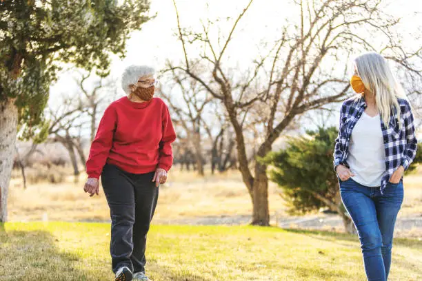 Photo of Mature Adult Female and Senior Adult Female Wearing Face Masks and Demonstrating Social Distancing Due to Infectious Virus Outbreak Pandemic