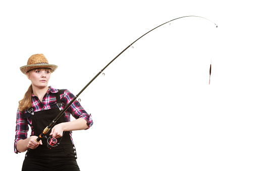 Spinning equipment, angling, cheerful fisherwoman concept. Focused woman in sun hat holding fishing rod hunting and fighting with fish on hook