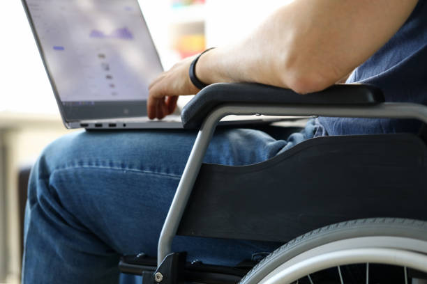 istock Man sitting in wheelchair working with laptop computer 1217304523