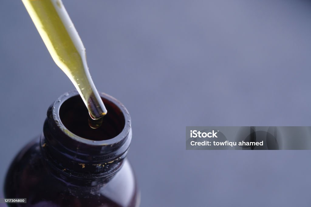 dispensing drops of healthy herbal medicinal oil dispensing drops of healthy herbal medicinal oil. Cannabis Plant Stock Photo