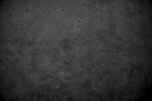 Dark polished beton wall with visible bubbles-air eyes - original flat surface with a beautiful texture of raw stone - slight surface porosity with vertical stains visible - abstarct concrete stock photo