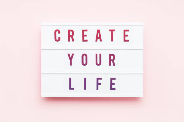istock CREATE YOUR LIFE written in light box on pink background. Motivation quote. Top view. 1217311425