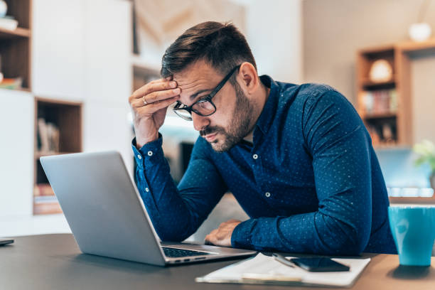 Home office Tired young businessman working at home using lap top and looking Anxious eastern european descent stock pictures, royalty-free photos & images