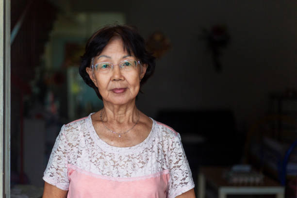 Portrait shot of a confident senior Asian woman standing in front of her house