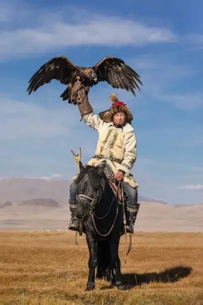 Photo of A young eagle hunter with his eagle and horse.