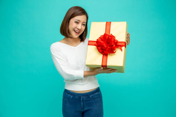 happy beautiful asian woman smile with gold gift box isolated on green background. teenage girls in love, receiving gifts from lovers. new year or christmas concept - suitor imagens e fotografias de stock